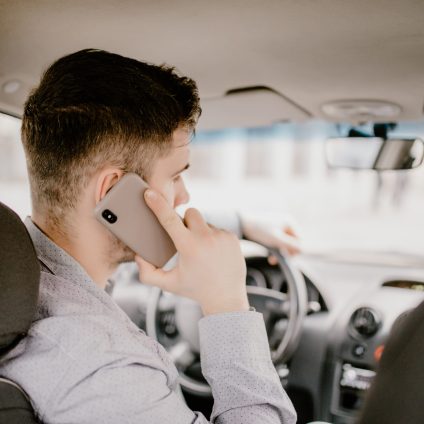 Young man talking on cell phone while driving and overtaking, not paying attention to the road and traffic.